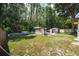 Large backyard with lush greenery, white picket fence, and storage sheds in a wooded area at 5346 Black Pine Dr, Tampa, FL 33624