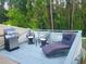 Back deck with grill, chairs, and chaise lounge, perfect for outdoor relaxation and entertaining overlooking the wooded area at 7010 Kendall Heath Way, Land O Lakes, FL 34637