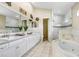 Bright bathroom featuring a soaking tub, dual sinks, and glass-enclosed shower at 7101 Bucks Ford Dr, Riverview, FL 33578