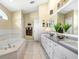 Bathroom with a soaking tub, tiled walls, and dual sink vanity at 7101 Bucks Ford Dr, Riverview, FL 33578