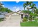 Charming single-story home with a three-car garage, landscaped lawn, and mature palm trees on a sunny day at 7101 Bucks Ford Dr, Riverview, FL 33578