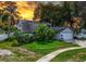 Charming home with a well-manicured lawn, palm trees, and attached garage at sunset at 7111 Lawnview Ct, Tampa, FL 33615