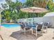 Outdoor patio featuring a dining set, lounge chairs, and tropical landscaping near the pool at 7111 Lawnview Ct, Tampa, FL 33615