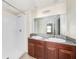 Bathroom with double vanity sinks, granite countertops, brown cabinets, and white tiled shower at 7211 Ozello Trail Ave, Sun City Center, FL 33573