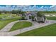 An elegant home with a circular driveway and lush lawns, framed by mature trees and a pond at 7301 Loghouse Rd, Plant City, FL 33565