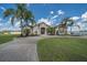 Beautiful home featuring manicured lawns and landscaping, complemented by palm trees and a circular driveway at 7301 Loghouse Rd, Plant City, FL 33565