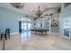 Bright game room boasts a pool table, travertine tile floors, elegant chandeliers, and access to the outdoor living area at 7301 Loghouse Rd, Plant City, FL 33565