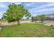 Spacious backyard with green grass, mature trees, and a white fence surrounding a screened-in pool area at 734 Flamingo Dr, Apollo Beach, FL 33572