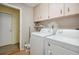 This laundry room offers a convenient space with machines, overhead storage, and connections ready for use at 7810 Flintlock Dr, Port Richey, FL 34668