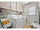 Functional laundry room with washer, dryer, utility sink, overhead cabinets, and a window for natural light at 7810 Flintlock Dr, Port Richey, FL 34668