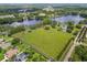 Aerial view of a spacious property featuring a large green field, mature trees, and a lake in the background at 820 Newberger Rd, Lutz, FL 33549