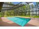 A sparkling screened-in pool surrounded by a lush green yard and mature trees at 820 Newberger Rd, Lutz, FL 33549