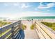 Stairway to a sunny beach with clear ocean views and people at 8485 Pelican Ln, Seminole, FL 33777
