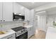 Renovated kitchen boasts white cabinets, stainless steel appliances, and new flooring at 8485 Pelican Ln, Seminole, FL 33777