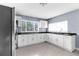 Modern kitchen with white cabinetry, dark countertops, stainless steel appliances, and large windows at 9310 N 12Th St, Tampa, FL 33612