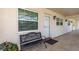 Exterior of the unit showcasing a bench seat, the front door, an exterior light fixture, and large window at 940 Virginia St # 303, Dunedin, FL 34698