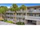 Three-story condo building with palm trees, white railings, and balconies with a peek of an outdoor dining area at 940 Virginia St # 303, Dunedin, FL 34698