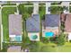 Aerial view of homes with dark roofs and green lawns, one featuring a pool, providing a neighborhood perspective at 31111 Bridgegate Dr, Wesley Chapel, FL 33545