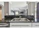 Close-up of a stainless steel double sink with black granite countertop, offering a view into the living room at 31111 Bridgegate Dr, Wesley Chapel, FL 33545