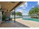 Relaxing covered patio featuring a ceiling fan, outdoor seating and overlooking a sparkling pool and lake at 31111 Bridgegate Dr, Wesley Chapel, FL 33545