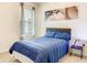 Cozy bedroom featuring a plush blue bed, window with blinds, and modern artwork at 10024 Merry Fawn Ct, Sun City Center, FL 33573