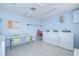 Well lit laundry room features multiple washers, a utility sink, tiled floors and a folding table at 11511 113Th St # 33D, Largo, FL 33778
