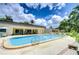 Community pool with lounge chairs, tables, and umbrellas on a sunny day with landscaping at 11511 113Th St # 33D, Largo, FL 33778