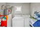 Functional laundry room with a washer, dryer, water heater, and ample storage space at 120 W Sligh Ave, Tampa, FL 33604