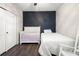 Cozy bedroom showcasing dark wood floors, a black accent wall, and a bed with white linens at 12415 Hitching St, Odessa, FL 33556