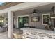 Outdoor kitchen with granite countertops, a built-in grill, a ceiling fan, and a TV at 12415 Hitching St, Odessa, FL 33556