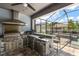 Outdoor kitchen under screened enclosure with stainless steel appliances, bar, and sink at 12415 Hitching St, Odessa, FL 33556