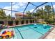 A sunny pool area inside an enclosure featuring a hot tub, and fun floats in a well-maintained outdoor space at 12415 Hitching St, Odessa, FL 33556