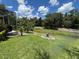 Landscaped backyard features a screened lanai overlooking a tranquil pond filled with lily pads and surrounding greenery at 1247 Gentilly Ln, Wesley Chapel, FL 33544