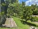 View of the backyard landscaping and greenery on a sunny day with the pool enclosure on the left at 1247 Gentilly Ln, Wesley Chapel, FL 33544