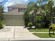 Charming home featuring a two-car garage and a well-manicured lawn with lush tropical landscaping at 1247 Gentilly Ln, Wesley Chapel, FL 33544