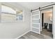 Bedroom with wood-look flooring, barn door access to bathroom, and exterior view at 13727 Gene Rossi Ave, Hudson, FL 34667