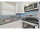 Bright kitchen showcasing stainless steel appliances, granite countertops, stylish backsplash, and white cabinetry at 13727 Gene Rossi Ave, Hudson, FL 34667