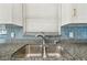 Close-up of a stainless steel kitchen sink with a modern faucet and gray granite countertops at 13727 Gene Rossi Ave, Hudson, FL 34667