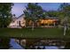 Backyard at dusk features a screened pool, patio, pond, and tranquil lighting at 16226 Carnoustie Dr, Odessa, FL 33556
