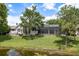 Inviting backyard featuring lush lawn, screened pool, patio, and serene water view at 16226 Carnoustie Dr, Odessa, FL 33556