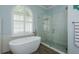 Modern bathroom equipped with a standalone tub, glass-enclosed shower, and wood-look tile floors at 16226 Carnoustie Dr, Odessa, FL 33556