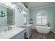 Charming bathroom featuring dual vanities, a soaking tub, and stylish maritime-themed décor at 16226 Carnoustie Dr, Odessa, FL 33556