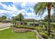 Elegant community entrance with lush landscaping, stone accents, and a view of the pond at 16226 Carnoustie Dr, Odessa, FL 33556
