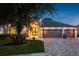 Charming single-story home featuring a well-manicured lawn, gray garage doors, and landscape lighting at 16226 Carnoustie Dr, Odessa, FL 33556