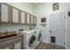 Well lit laundry room features sink, washer, dryer and wall cabinets at 16226 Carnoustie Dr, Odessa, FL 33556