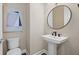 Modern powder room featuring a pedestal sink, round mirror, sleek fixtures, and geometric art at 16423 Sapphire Point Dr, Lakewood Ranch, FL 34211