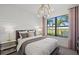 Bright bedroom featuring a large window with a view, elegant chandelier, and a comfortable king-sized bed at 16423 Sapphire Point Dr, Lakewood Ranch, FL 34211