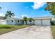 Charming single-story home featuring a well-manicured lawn, palm trees, and a two-car garage at 2165 Campus Dr, Clearwater, FL 33764