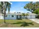 Charming single-story home featuring a well-manicured lawn, palm trees, and a two-car garage at 2165 Campus Dr, Clearwater, FL 33764