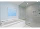 Modern bathroom with a white soaking tub, glass shower, and light gray tile at 301 1St S St # 1601, St Petersburg, FL 33701
